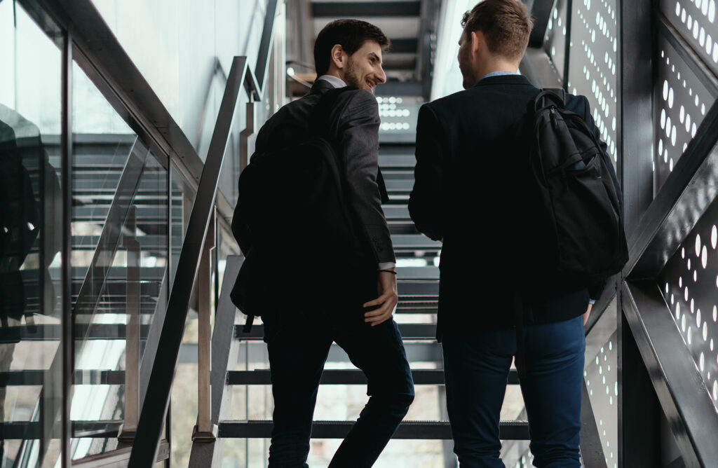 Two men going up, down stairs while chatting